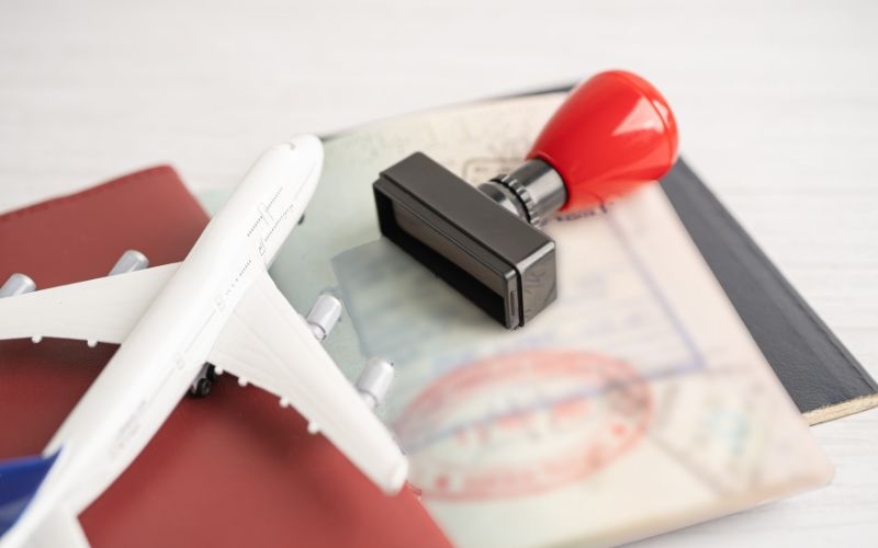 Toy airplane, passport with visa stamps, and a rubber stamp, symbolizing international travel and documentation