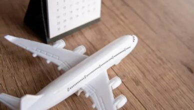 Toy airplane next to a calendar on a wooden surface, symbolizing travel planning